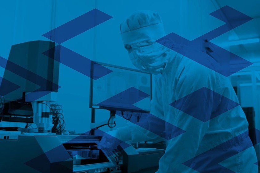 Ein*e Forscher*in im Reinraum bei der Arbeit mit hochpräzisen Geräten zur Mikro- oder Nanostrukturierung.