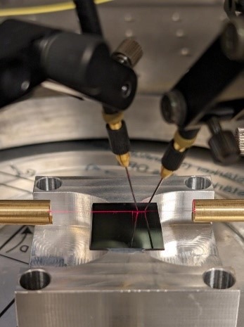 Halterungen mit sehr feinen Nadeln zur Charakterisierung photonisch integrierter Schaltkreise (PIC) für Anwendungen der Terahertzsensorik befinden sich über einem photonischen Element. Probes with very fine needles for characterizing photonic integrated circuits (PIC) for terahertz sensing applications positioned above a photonic element.