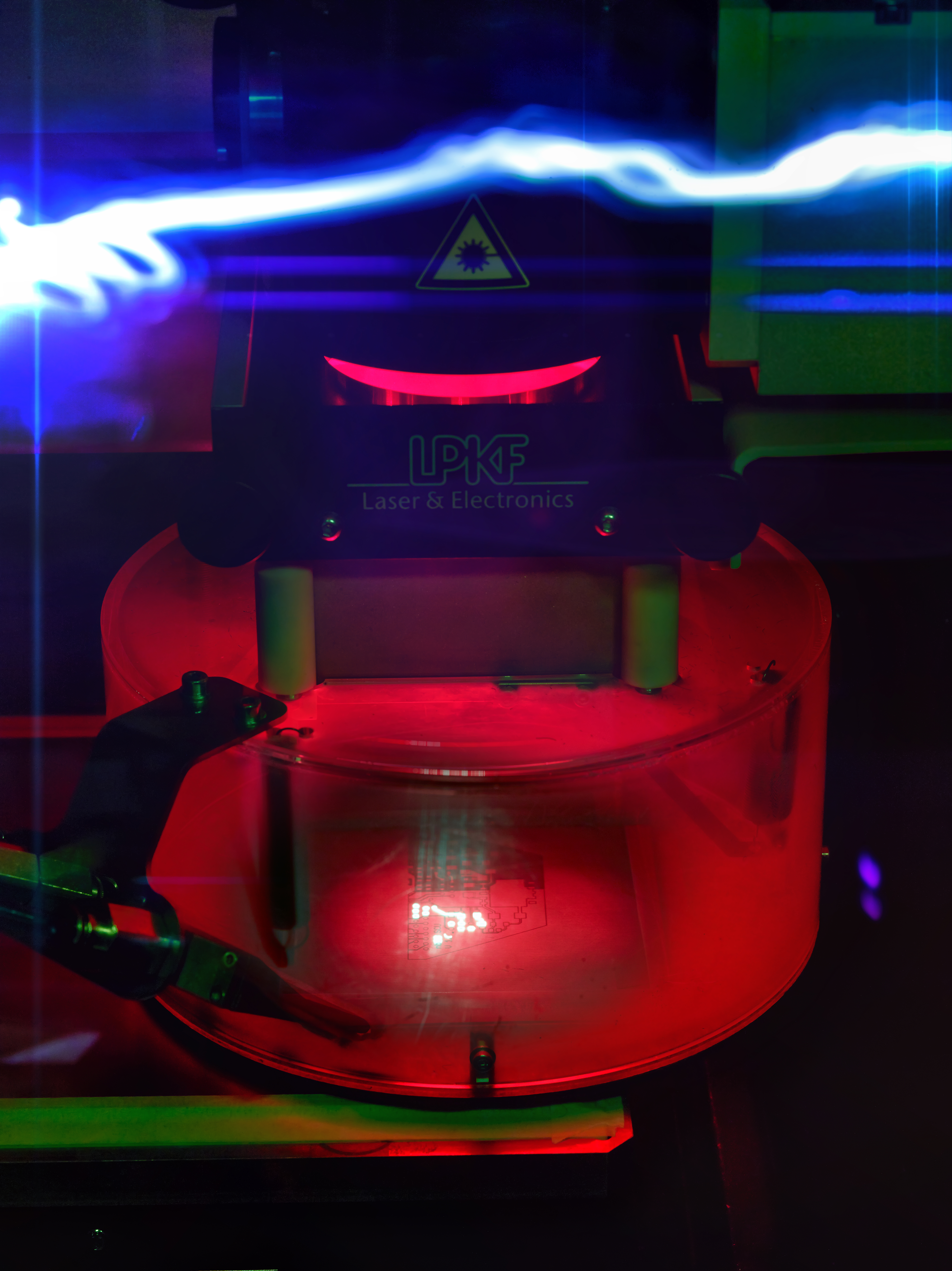 Eine Laserfräse zur präzisen Strukturierung von Platinen für Terahertzsenorik in rotem Licht. A laser milling machine for precise structuring of circuit boards for terahertz sensing, illuminated in red light.