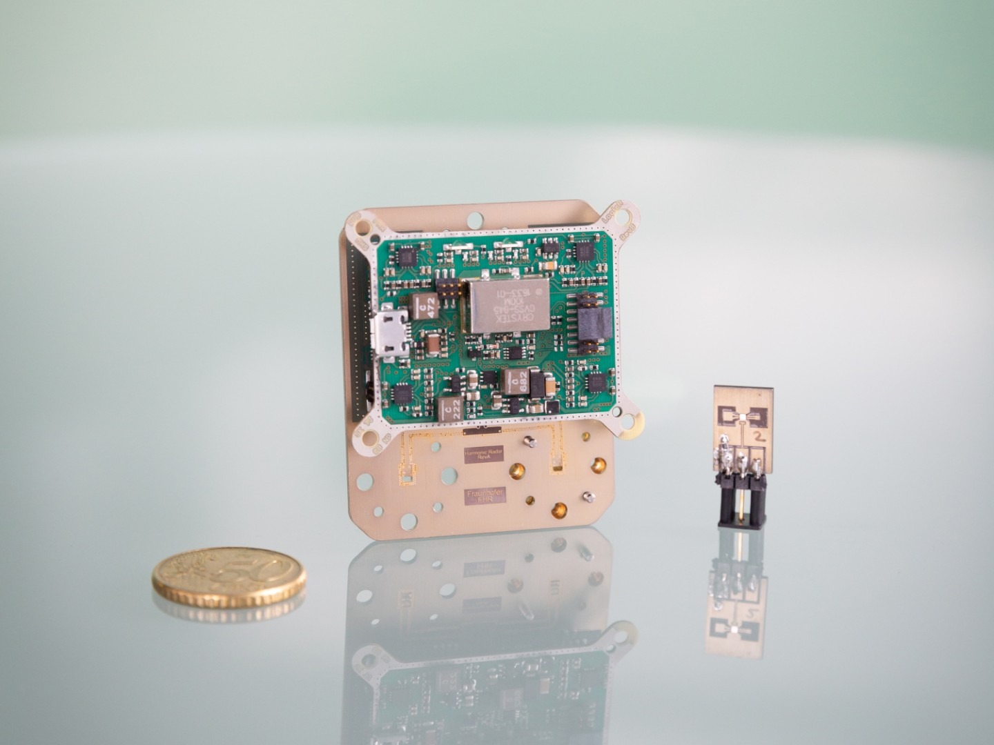 Kompaktes Radarsystem für Terahertzsensorik mit Harmonischen Tags neben einer Münze zum Größenvergleich. Compact radar system for terahertz sensing with harmonic tags placed next to a coin for size reference.