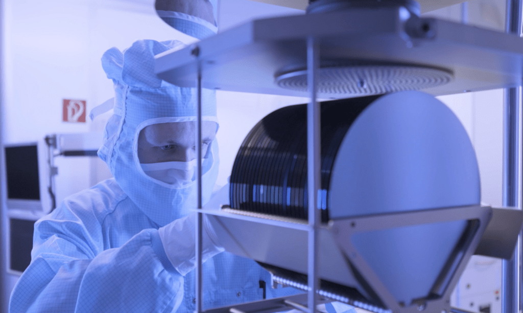 Person in Reinraumkleidung arbeitet an einem Stack mit Wafern für die Entwicklung von Terahertzsensorik. Person in cleanroom attire works on a stack of wafers for the development of terahertz sensing.