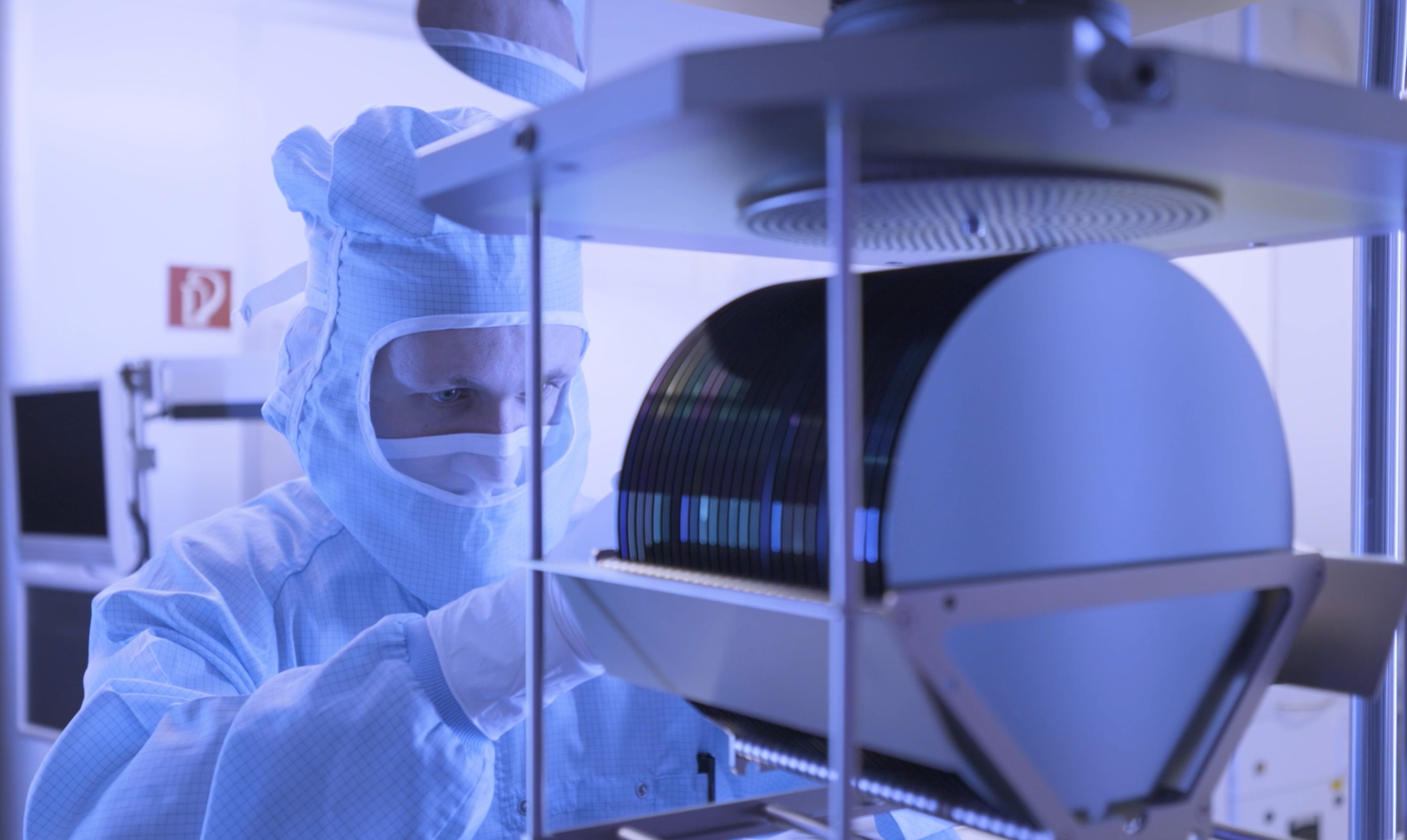 Person in Reinraumkleidung arbeitet an einem Stack mit Wafern für die Entwicklung von Terahertzsensorik. Person in cleanroom attire works on a stack of wafers for the development of terahertz sensing.