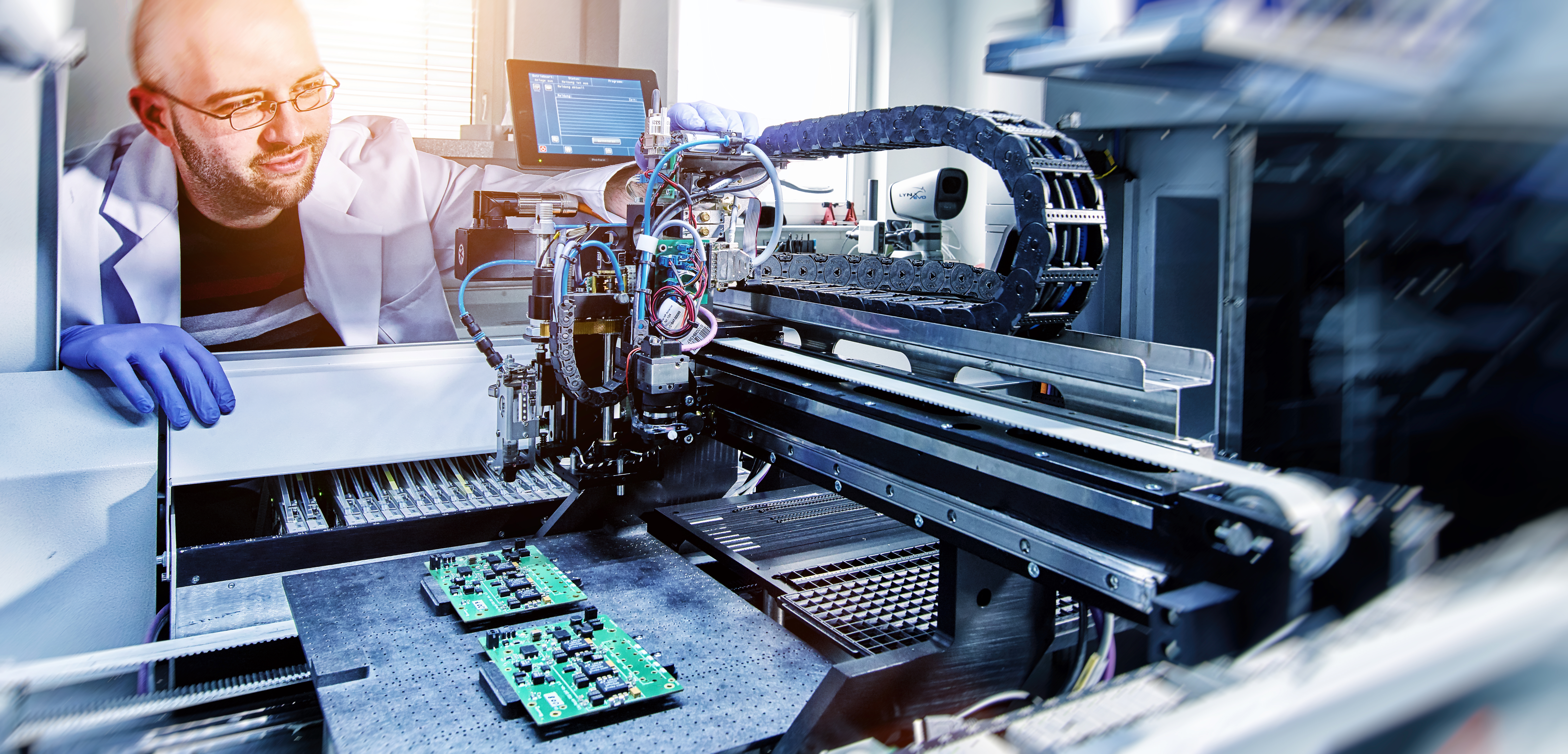 Ein Wissenschaftler bedient einen Bestückungsautomaten zur Fertigung von Platinen für Terahertzsensorik. A scientist operates a pick-and-place machine for manufacturing circuit boards for terahertz sensing.