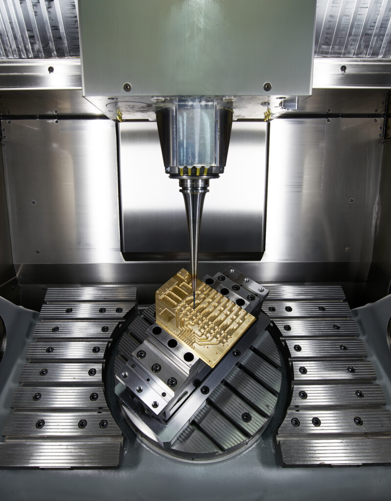 Eine 5-Achs-CNC-Maschine fräst ein Hochfrequenzbauteil für Terahertzsensorik aus einem Messingblock. A 5-axis CNC machine mills a high-frequency component for terahertz sensing from a brass block.