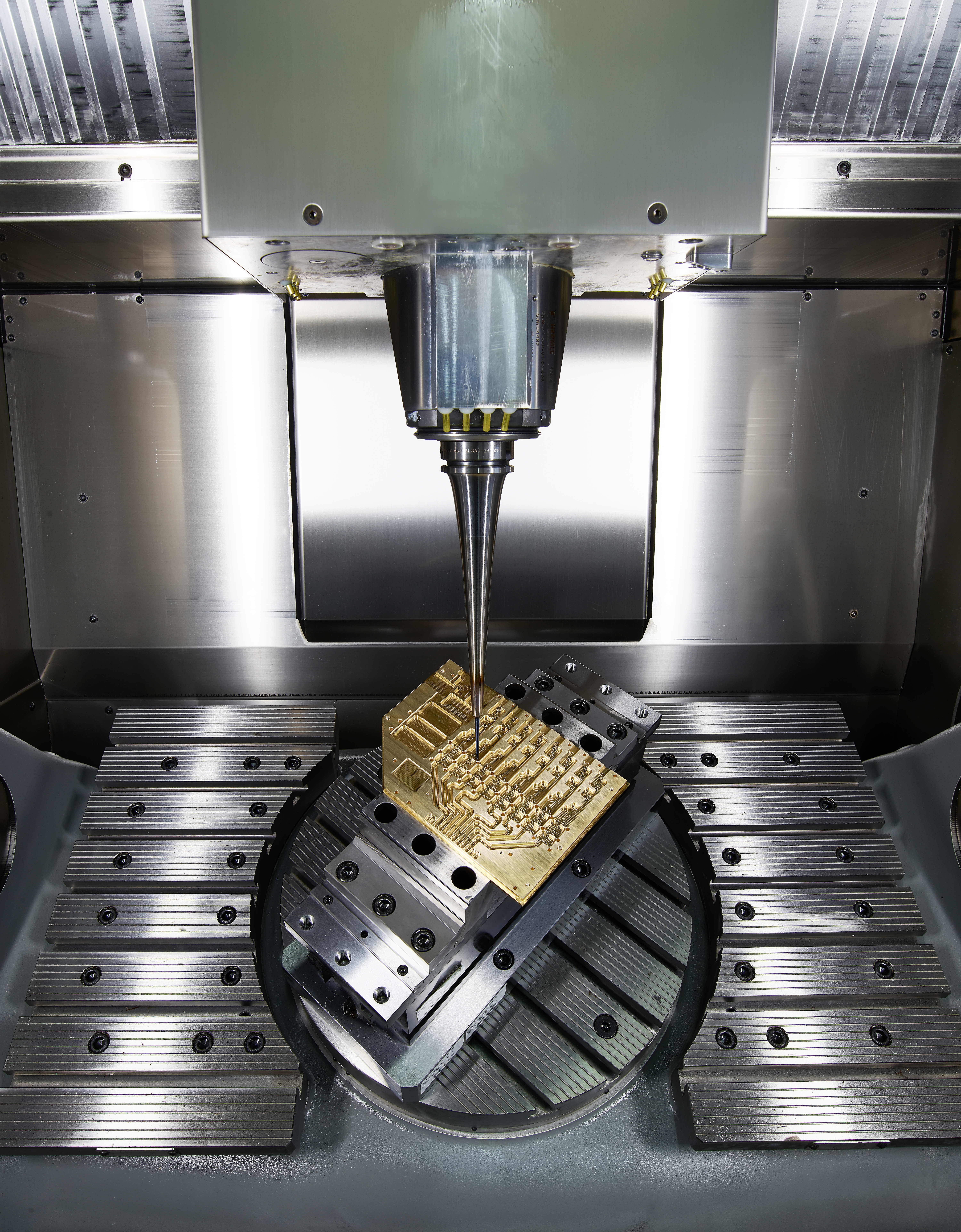 Eine 5-Achs-CNC-Maschine fräst ein Hochfrequenzbauteil für Terahertzsensorik aus einem Messingblock. A 5-axis CNC machine mills a high-frequency component for terahertz sensing from a brass block.